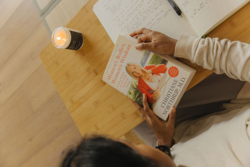 Divya reading Women's Bodies, Women's Wisdom by candlelight